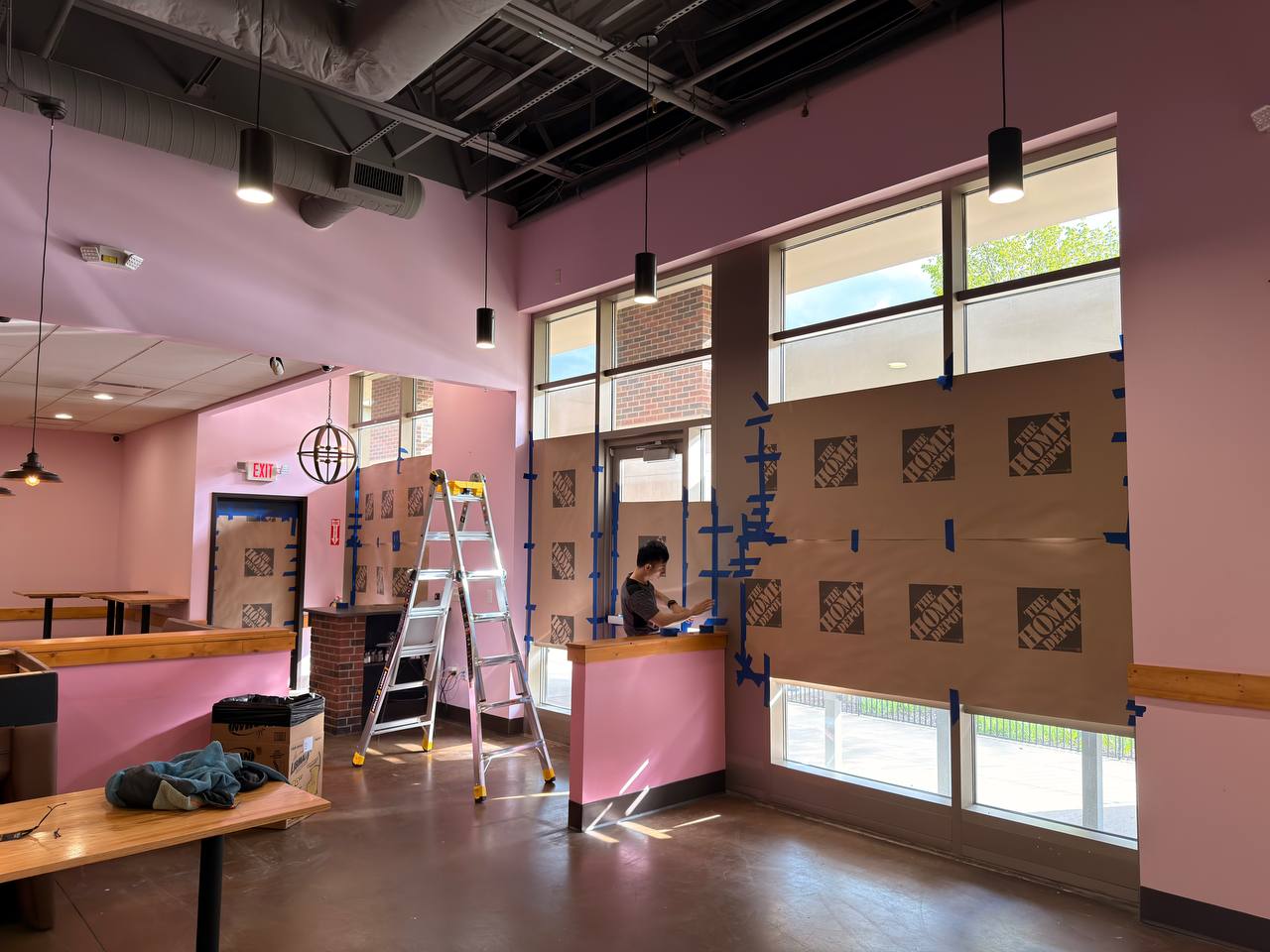 Storefront windows being prepped with temporary covering during buildout