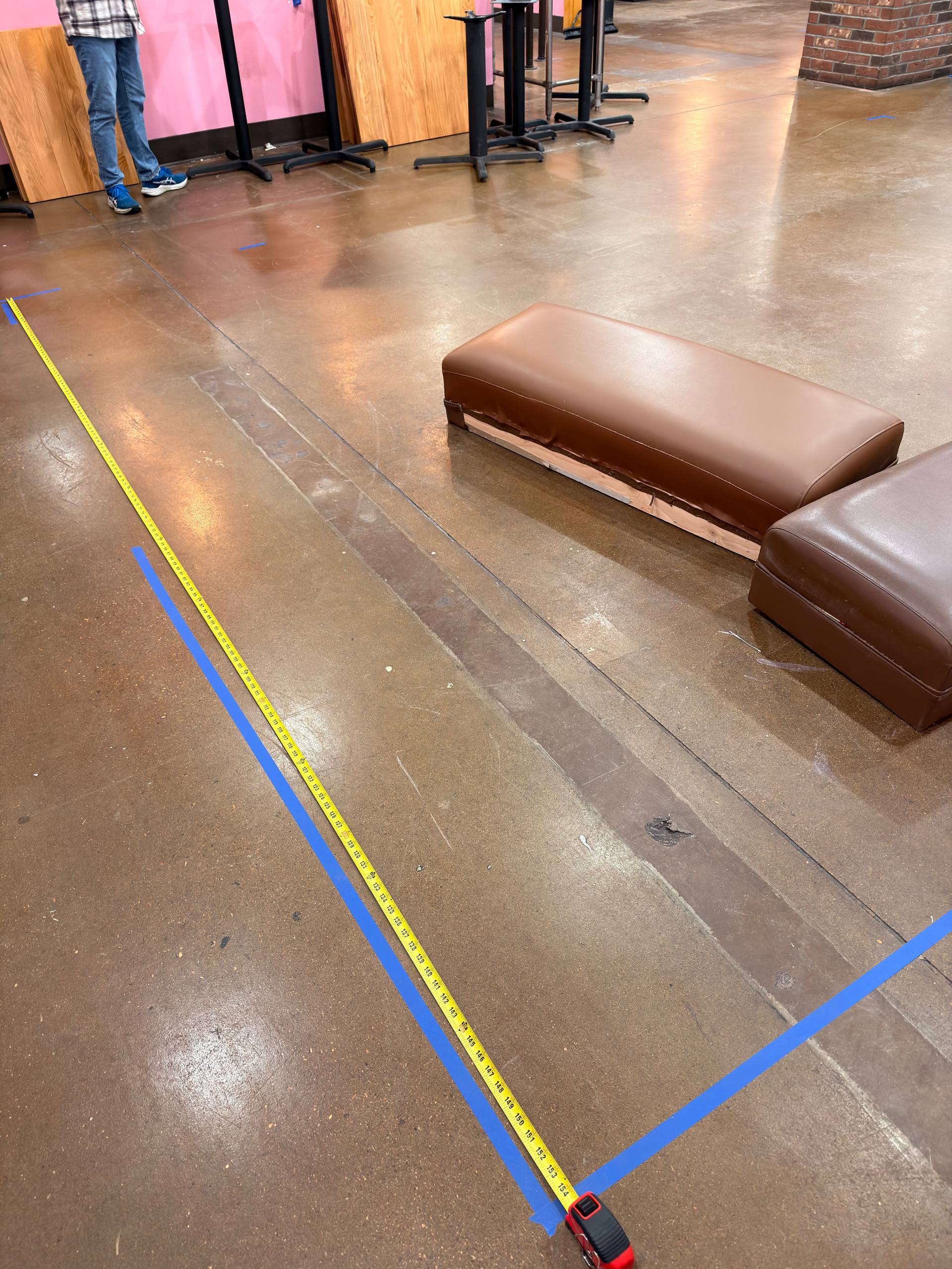 Tape measure and blue floor markings used to check aisle clearance for robot delivery routes