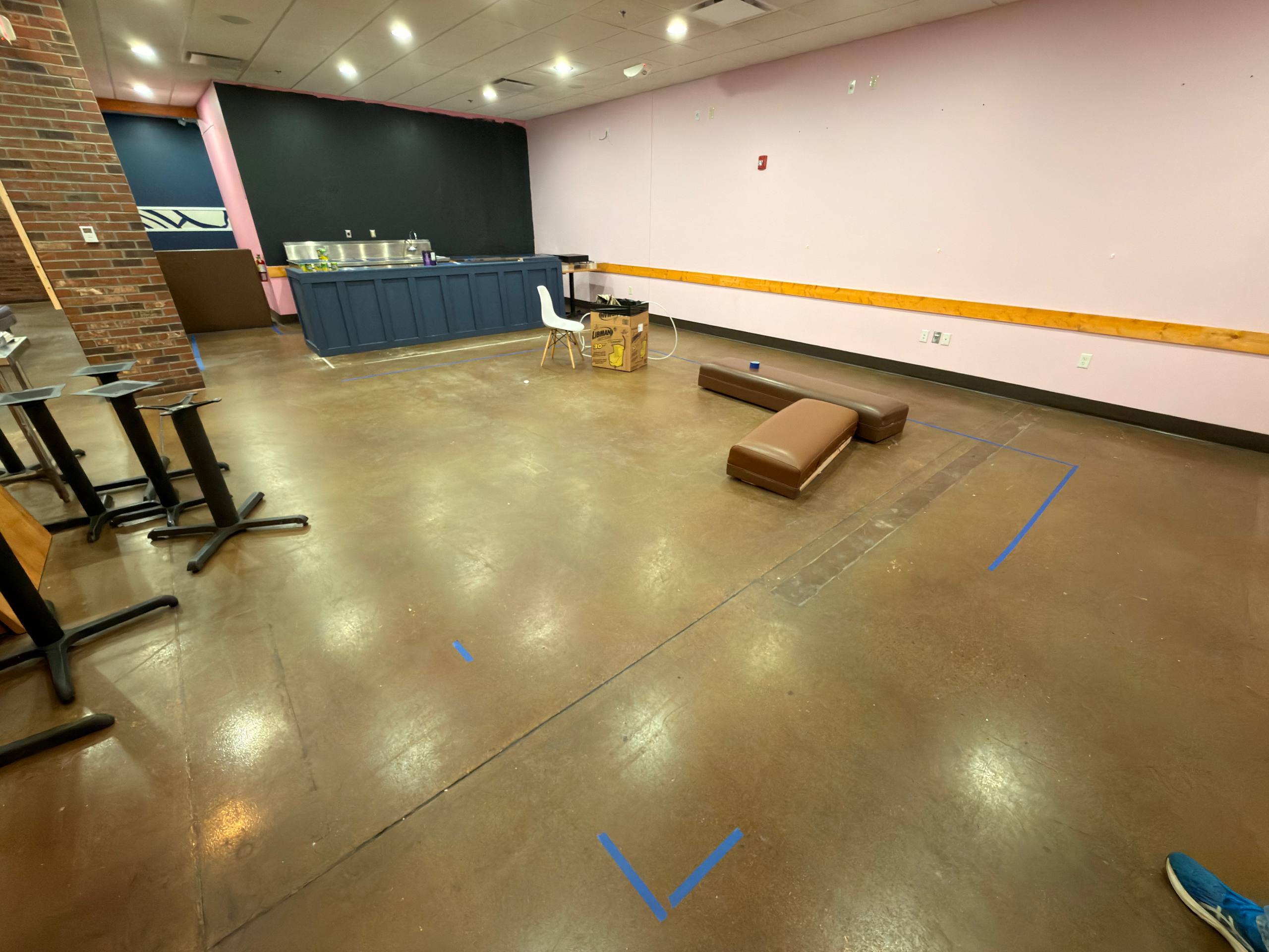 Front-of-house floor marked with blue tape for seating layout and robot delivery route planning